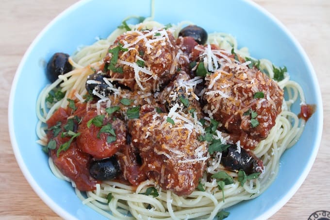 beef meatballs and spaghetti served in a blue bowl topped with cheese