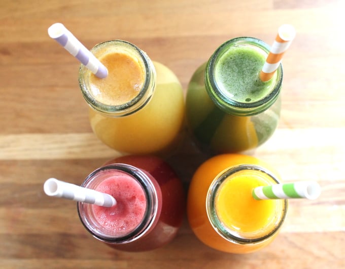 four bottles of juice with straws in viewed from above