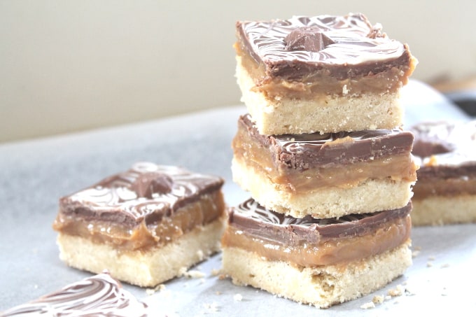 millionaire shortbread squares topped with chocolate stars in a stack on greaseproof paper.