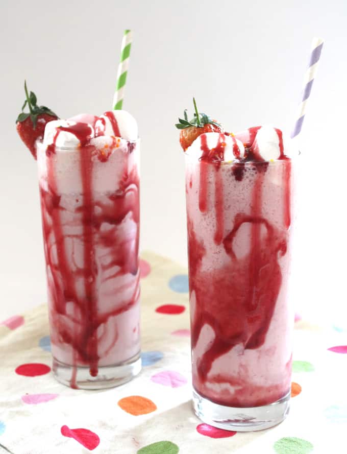  2 glasses of strawberry frozen yogurt milkshake sitting on top of a polka dot napkin