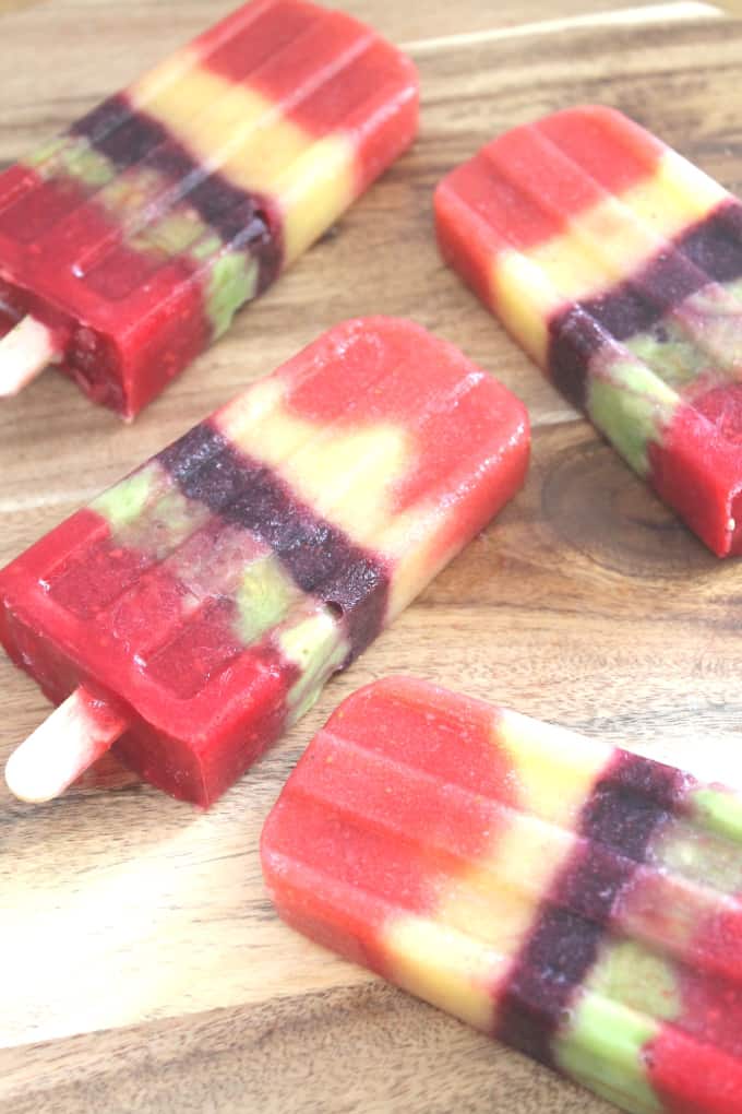 multi coloured fruit ice lollies on a wooden board