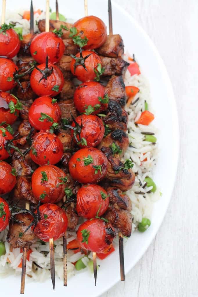 Balsamic Chicken Tomato Skewers on top of wild rice served on a white plate