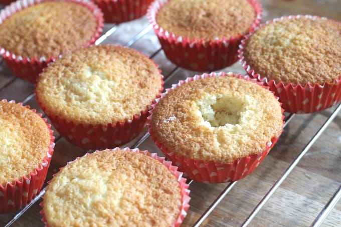 cupcakes on a wire rack with a hole in the centre of one of the cupcakes