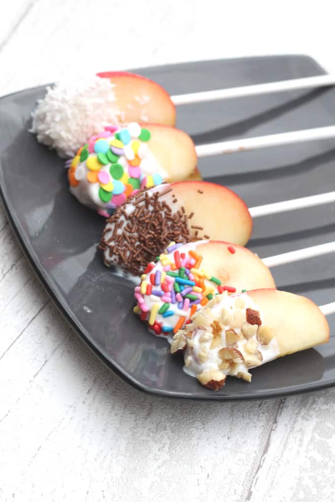 decorated apple and yogurt pops on a black plate