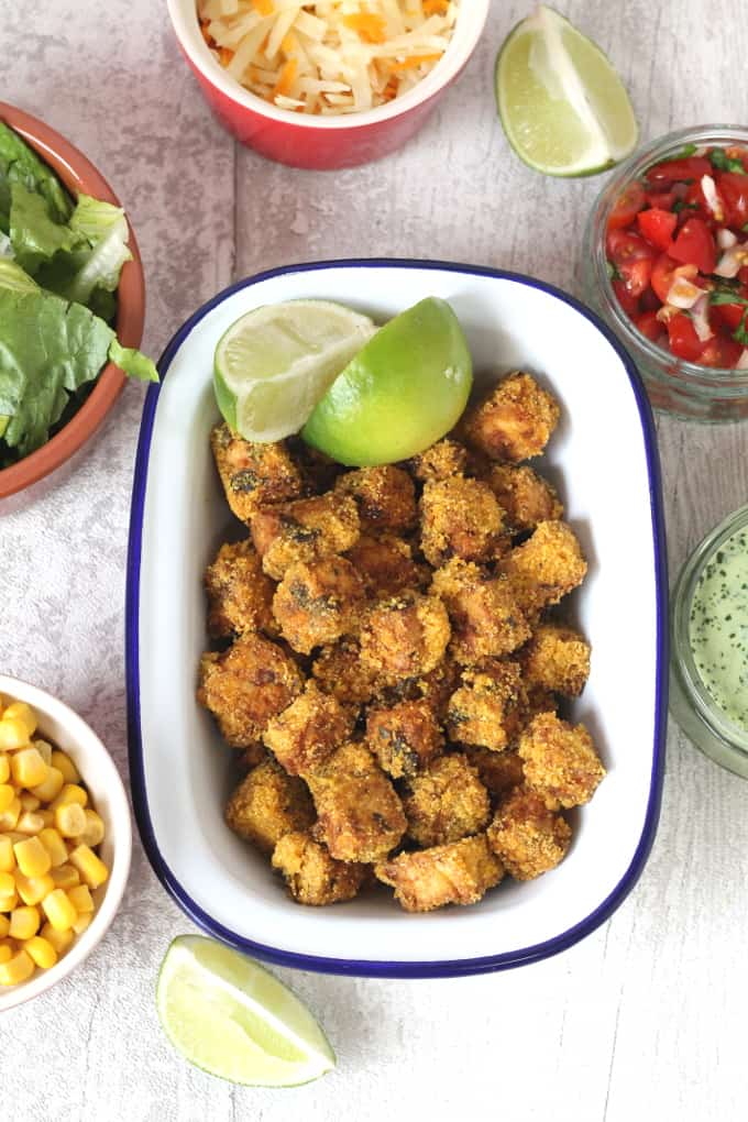 crispy tofu in a blue and white oven proof dish with 2 quarters of lime on top