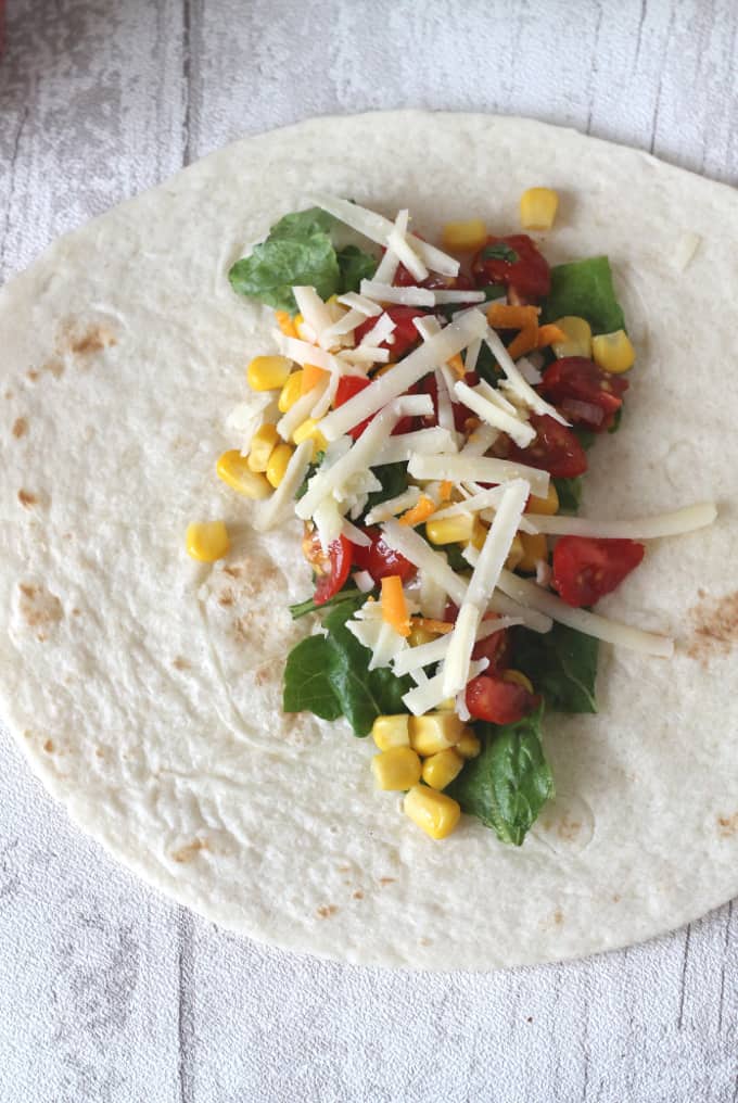 tortilla wrap with shredded lettuce, sweetcorn, tomato, grated cheese on top