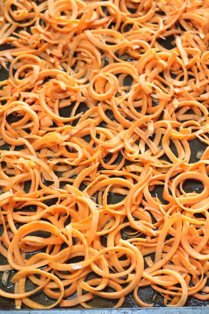 sweet potato curly fries on an oven tray with oil