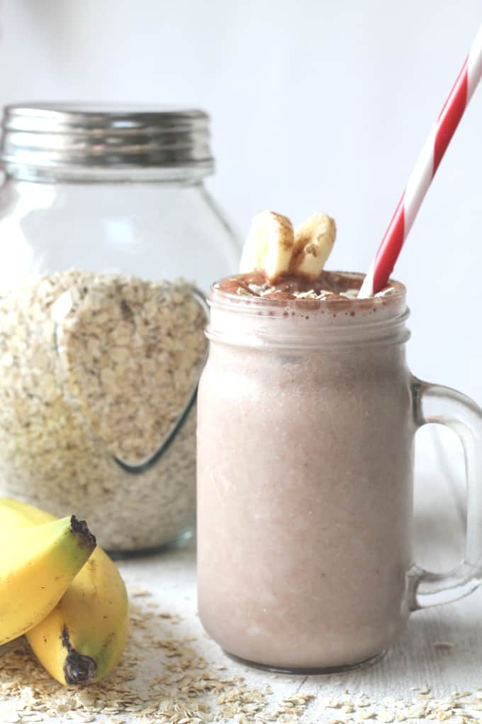 banana oat breakfast smoothie in a mason jar glass with a red and white striped star and some banana slices on the side of the glass.