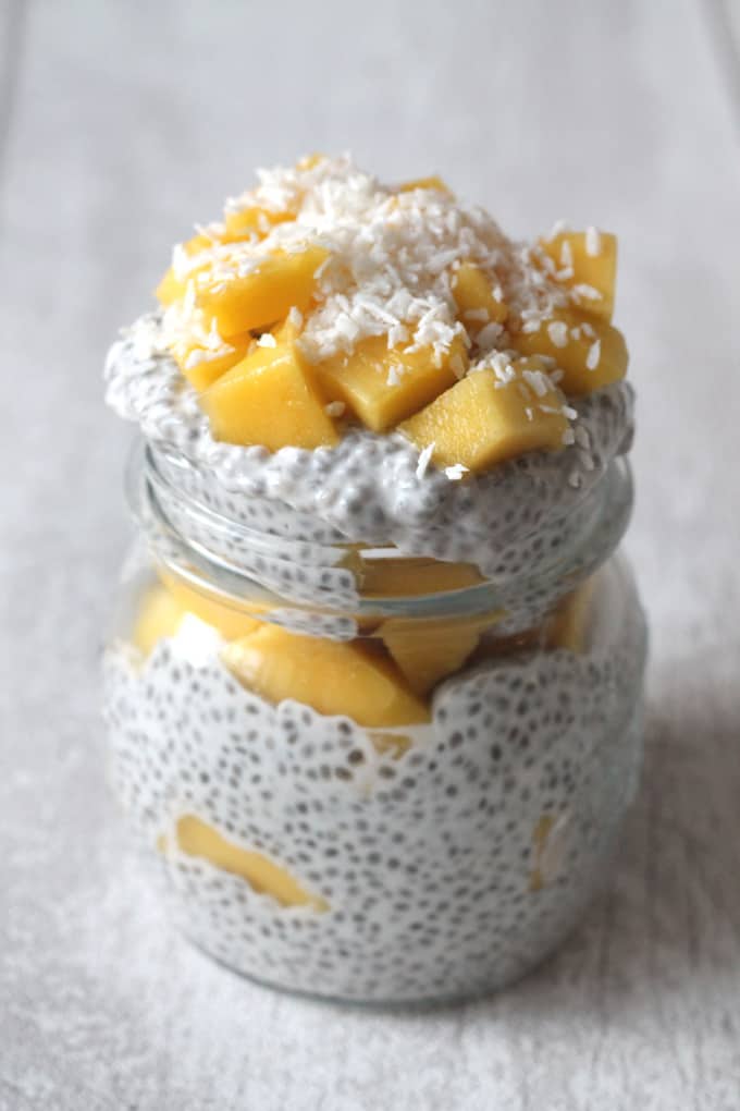 mango coconut chia pudding in a glass mason jar topped with coconut flakes