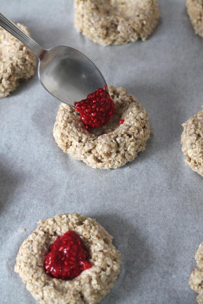 oatmeal thumbprint cookies being filled with raspberry chia jam
