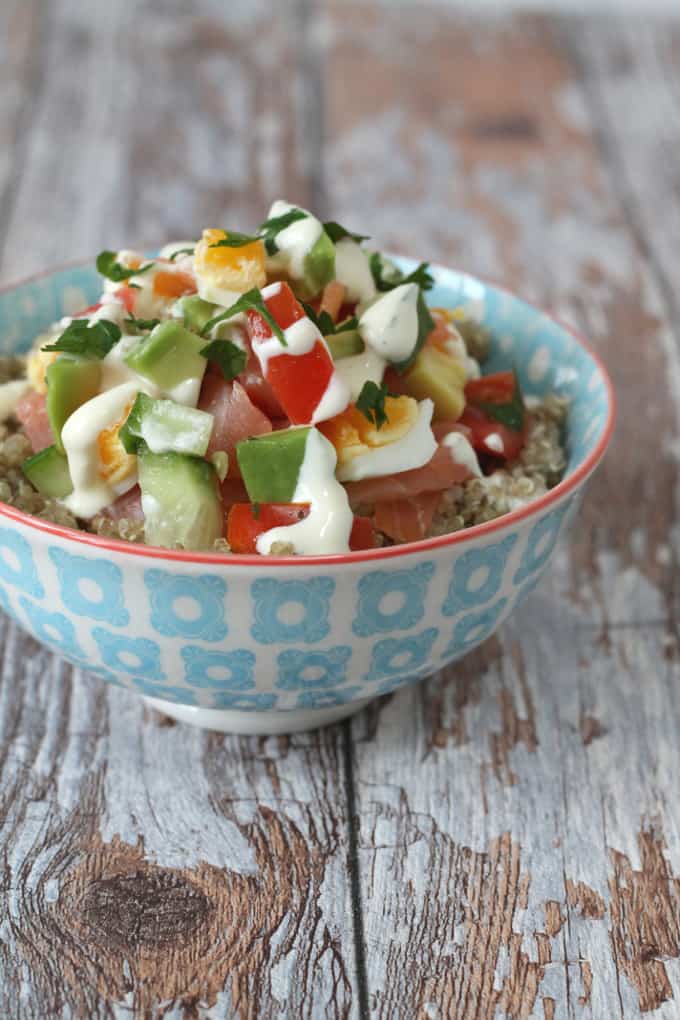 Smoked Salmon, Egg & Avocado Quinoa Bowl served in a small blue and white bowl on a wooden worktop