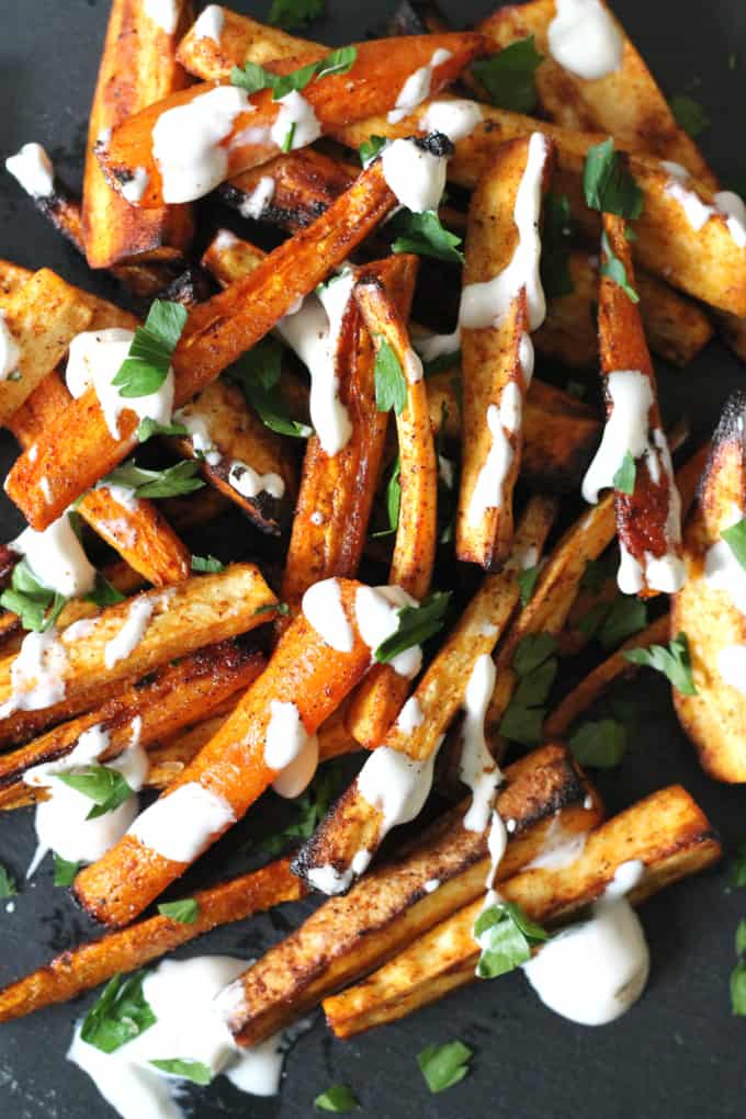 carrot parsnip fries on a black slate board drizzled with creme fraiche