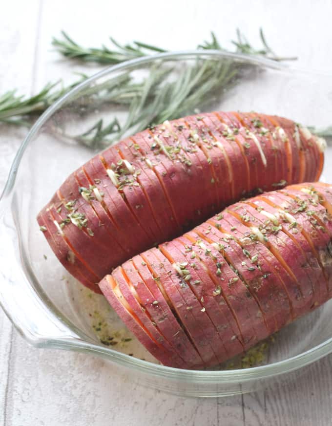 garlic herb hasselback sweet potatoes in a glass ovenproof bowl