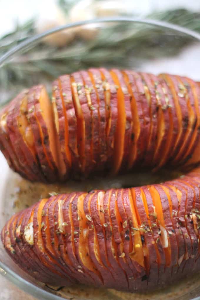 the cooked garlic oregano hasselback sweet potato in a glass ovenproof dish