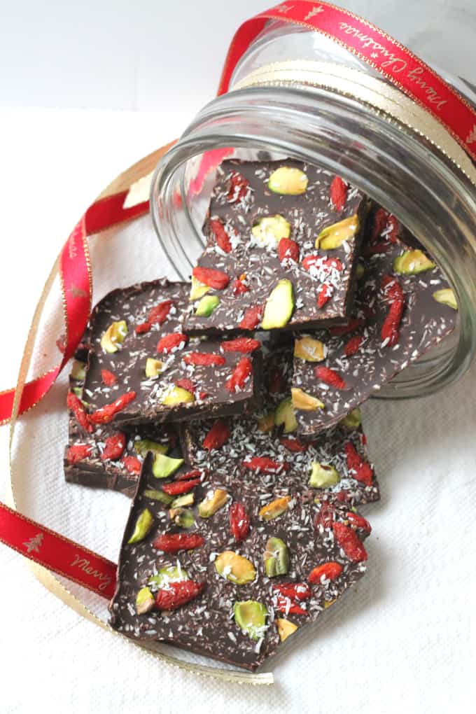 Superfood chocolate Bark falling out of a glass jar adorned with Christmas ribbons