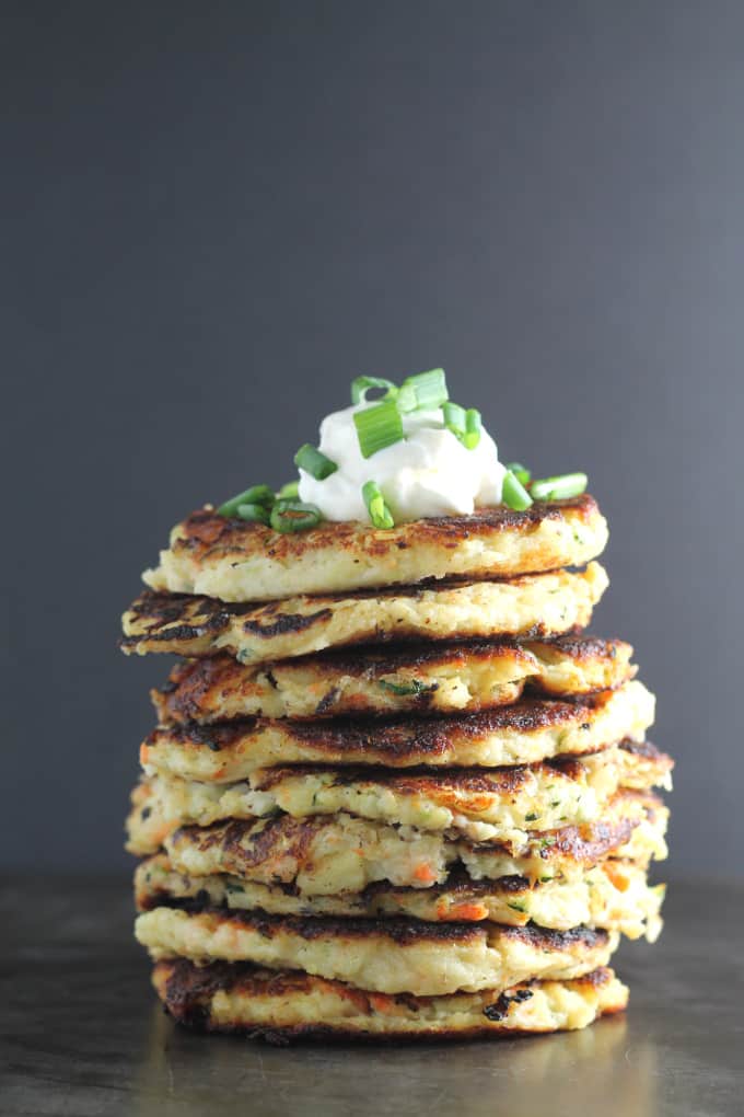 bubble & squeak fritters stacked in a pile with a dollop of creme fraiche and garnished with chopped spring onion