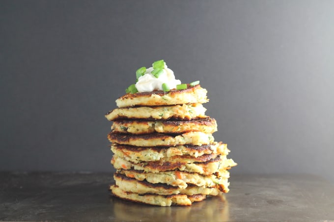 bubble and squeak leftover vegetable fritters in a stack with a dollop of creme fraiche on top and garnished with chopped spring onion