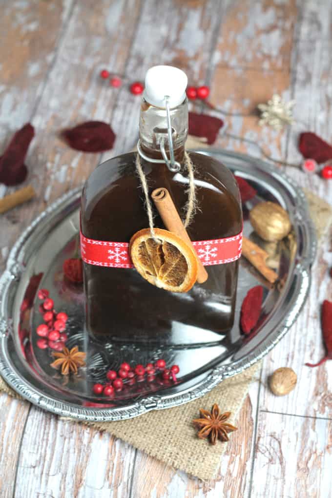 homemade mulled wine syrup in a glass bottle. Decorated with a dried orange slice and a cinnamon stick and a christmas ribbon