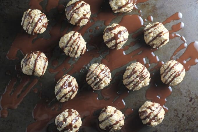 nut butter energy bites on a baking tray drizzled with melted chocolate
