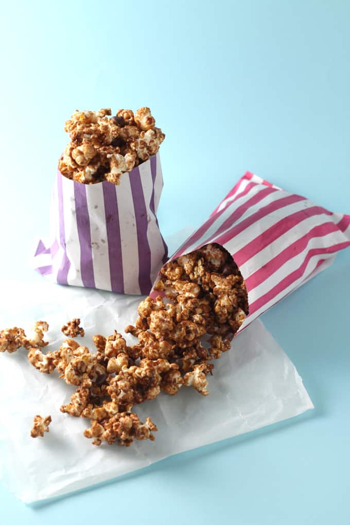 two striped bags filled with salted caramel chocolate popcorn on a blue background