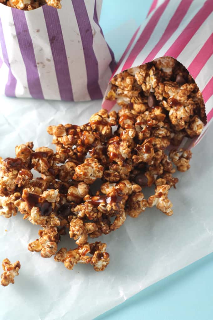 salted caramel chocolate popcorn falling out of a pink striped paper bag