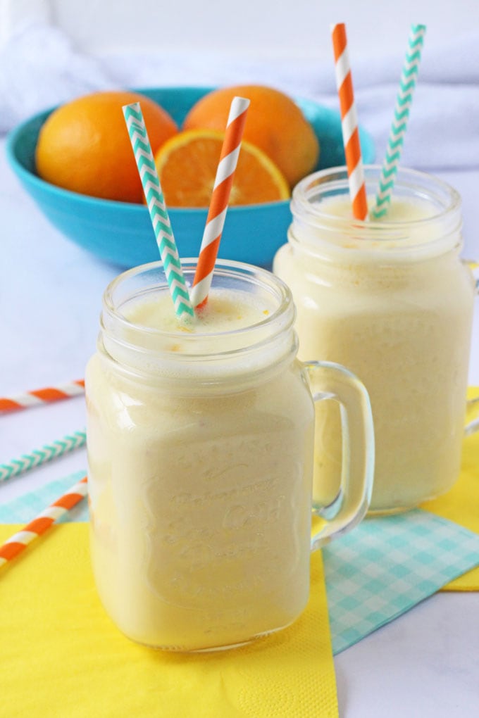 2 sunshine orange smoothies in mason jar jugs with colorful straws in them