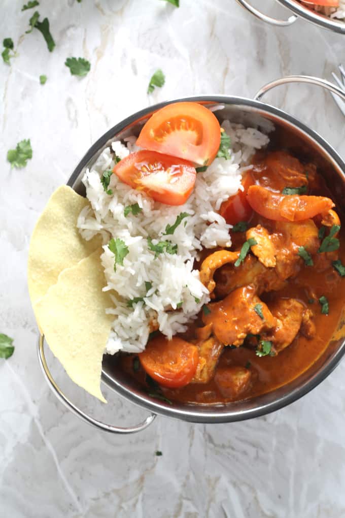 close up of the curry in the silver bowl with rice and the bits of poppadom also in the bowl