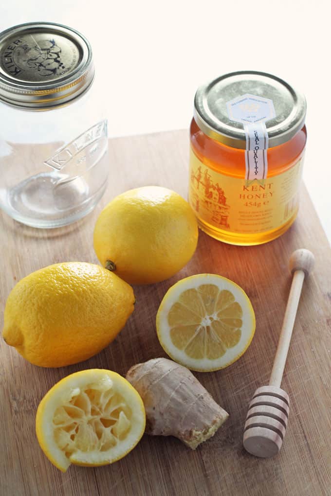 honey, lemon & ginger jar cold flu remedy ingredients on a wooden chopping board
