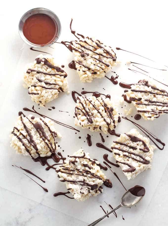 healthy coconut rice krispie puffed rice snacks drizzled with melted chocolate on a white marble background