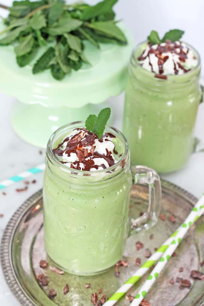 2 healthy shamrock shakes in glass mugs on a silver serving platter with two green straws