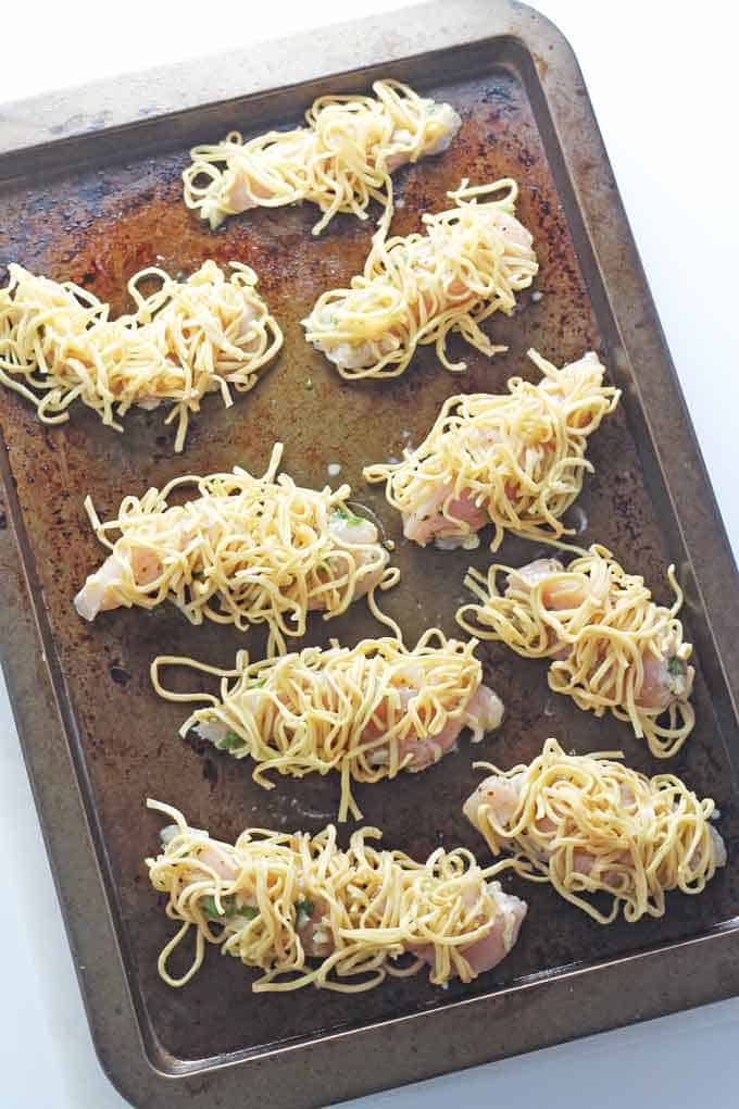 the prepared noodle wrapped chicken on a baking tray ready to go in the oven