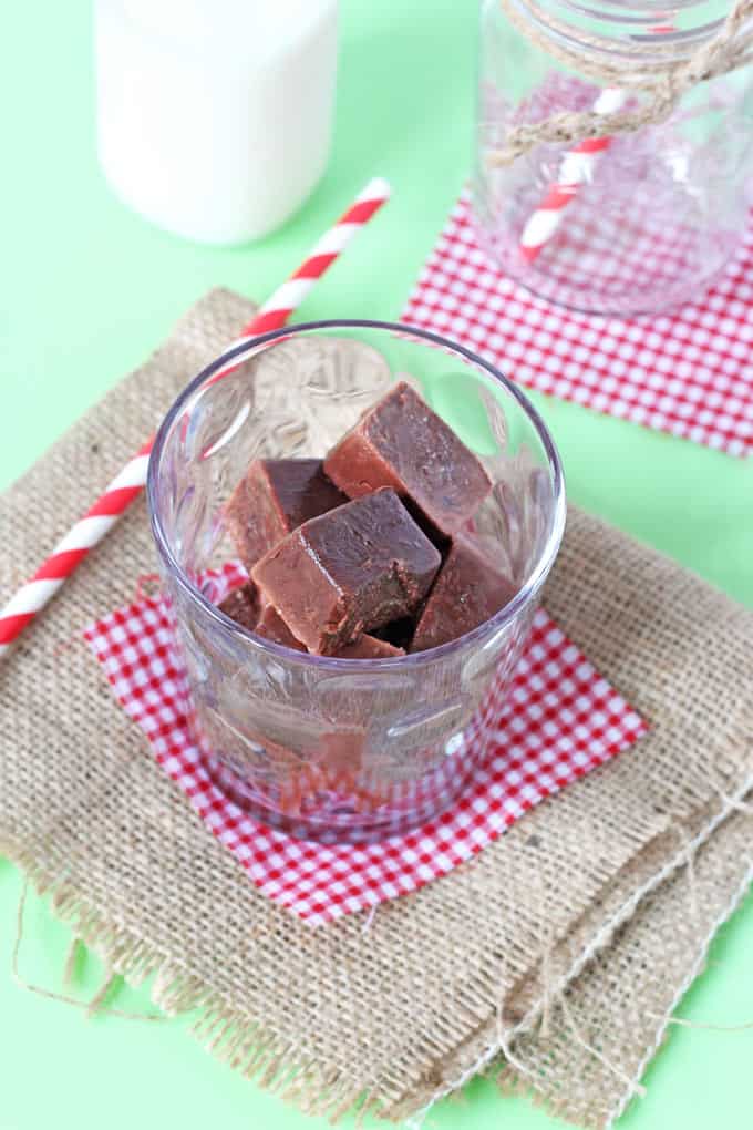 Chocolate Milk Ice Cubes in a small glass on top of a red and white gingham napkin with a red and white striped straw laying next to it