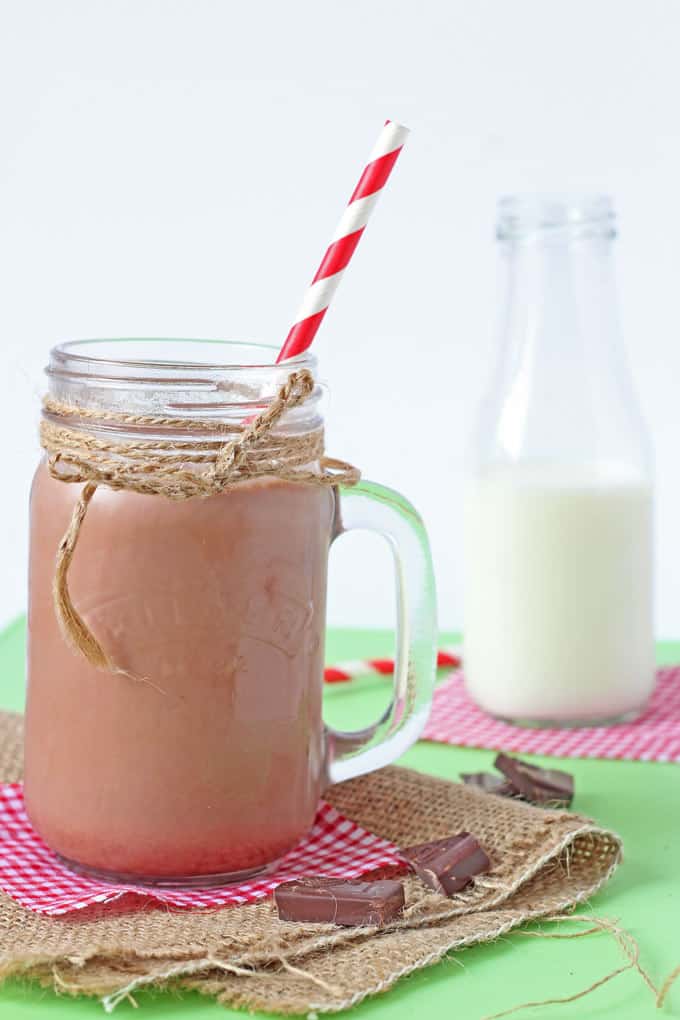 the finished chocolate milk in a mason jar with a red and white striped straw in it.
