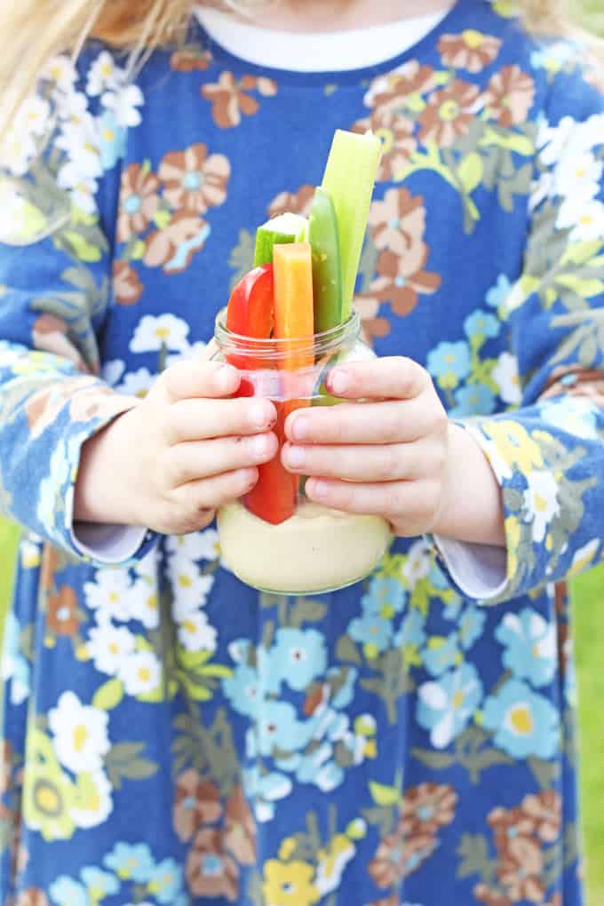 child holding hummus and crudites in a jar