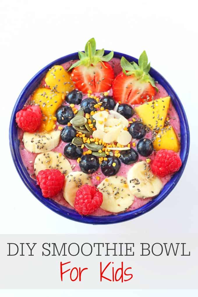 DIY Smoothie Bowl topped with fruit, berries and seeds in a blue bowl on white background