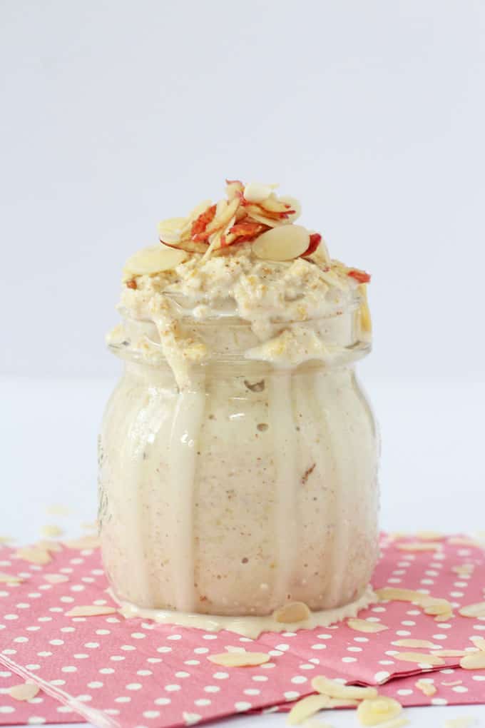 Apple & almond butter overnight oats served in a glass jar, and garnished with flaked almonds.