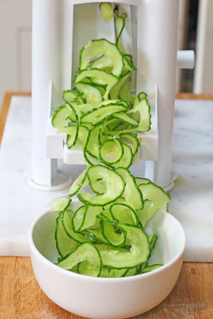 spiralizer with lots of spiralized cucumber coming out of it