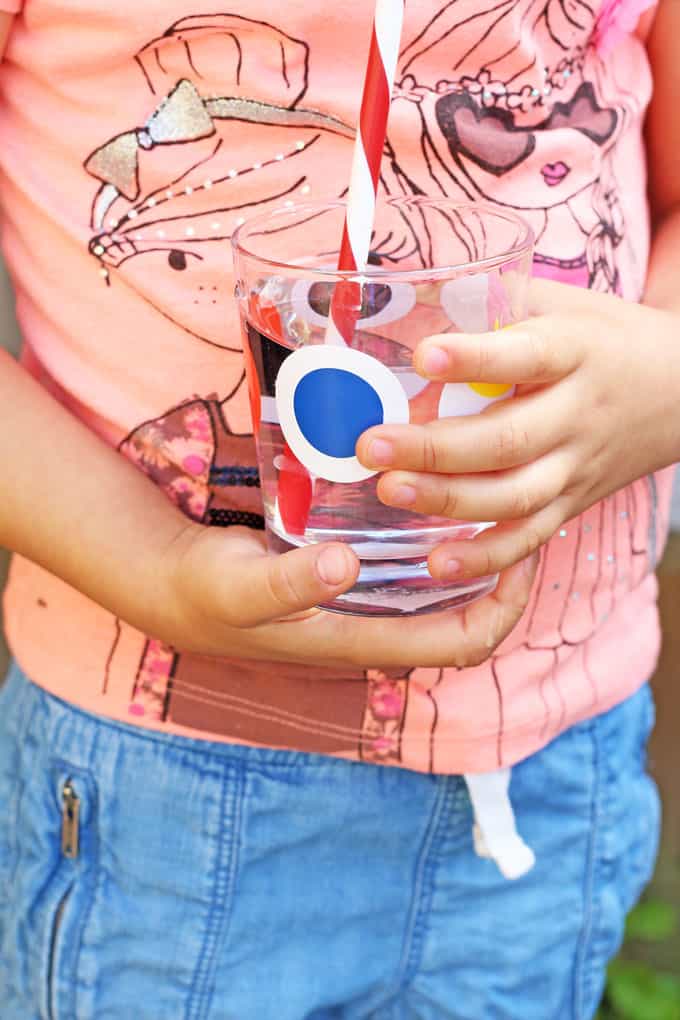 child holding a glass of water with a straw in it.