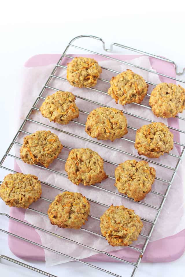 12 carrot, apple & oat breakfast cookies on a wire cooling rack on top of a pink chopping board