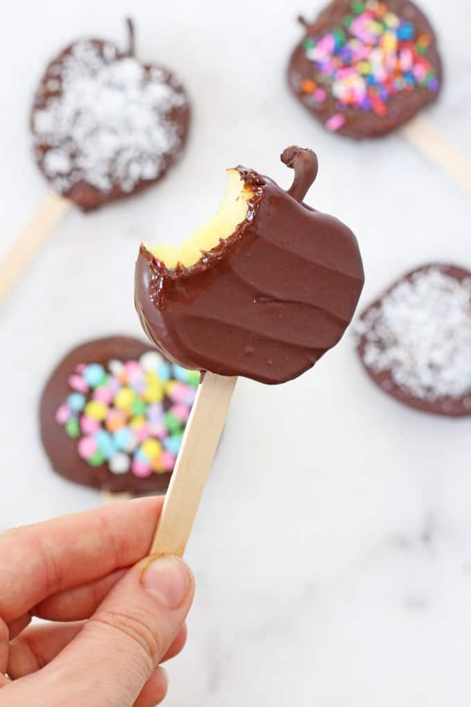 a chocolate toffee apple slice on a wooden popsicle stick