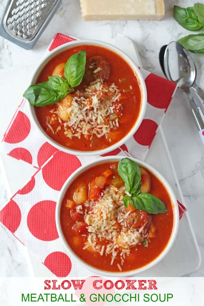 Italian Meatball & Gnocchi Soup in white bowls topped with finely grated cheese and fresh basil leaves.