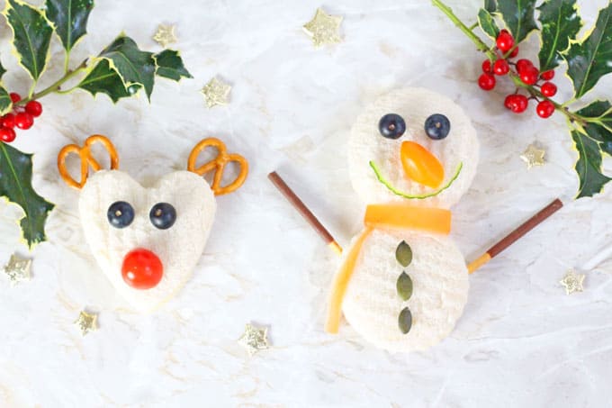 Rudolph and Snowman shaped sandwiches with holly and gold stars in the background