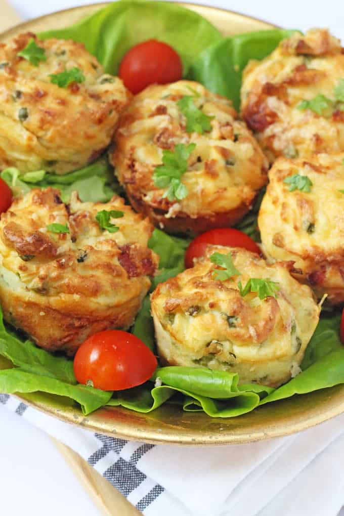 A plate of mashed potato, ham, cheese and pea muffins with lettuce leaves and halved cherry tomatoes.