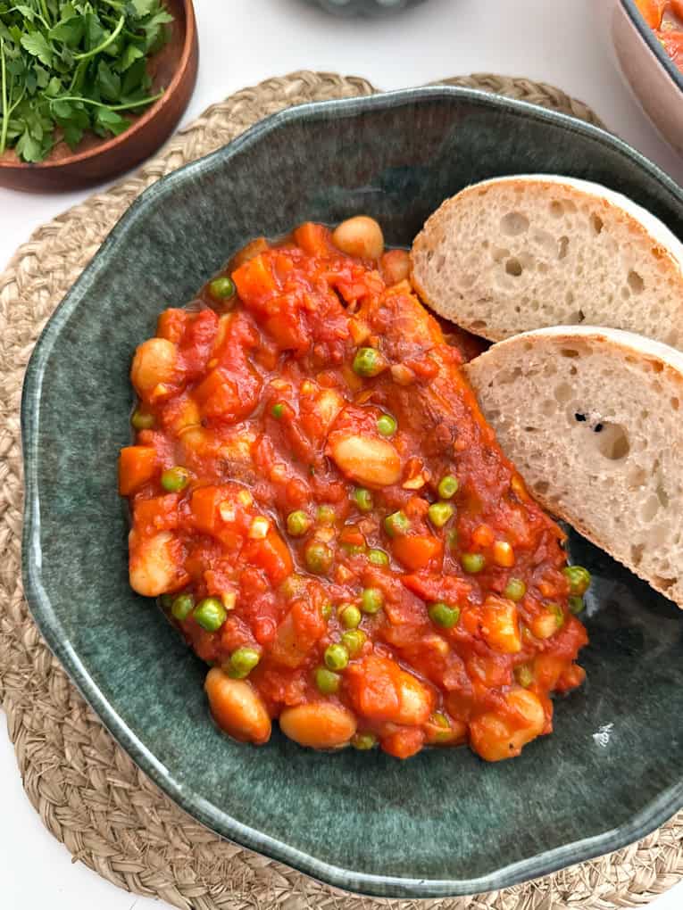 Sausage & Butterbean Casserole in a green ceramic bowl with two slices of white crusty bread.