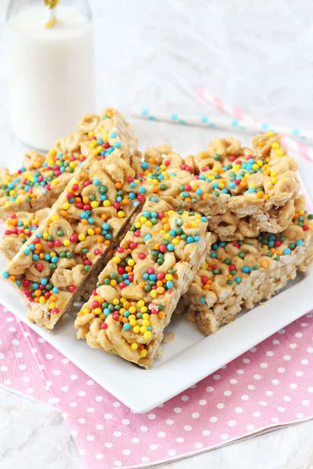 Cheerio Bars stacked on a white plate with small bottle of milk in the background