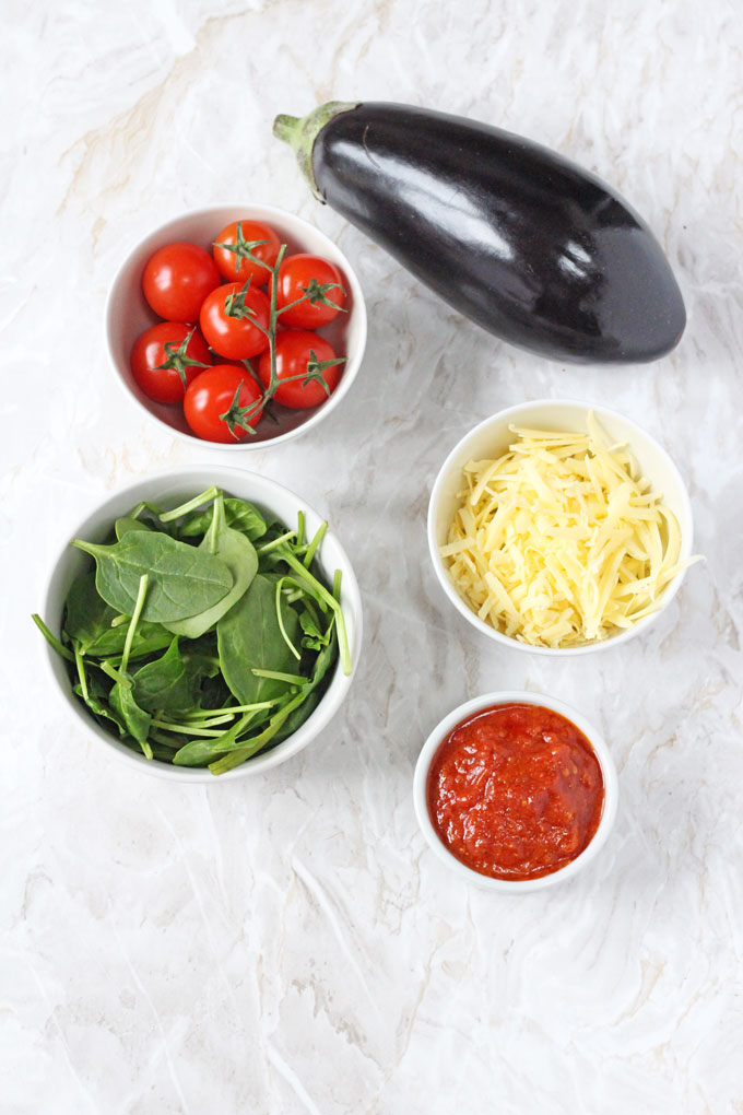 mini aubergine pizza ingredients in white ramekin dishes on a white  marble surface