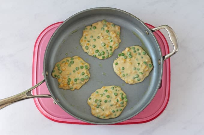 Pea & Sweetcorn Fritters in a frying pan