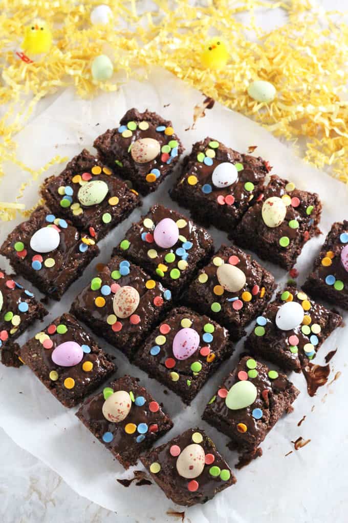 Mini Egg Brownies divided into equal squares and decorated with mini eggs and colorful sprinkles.