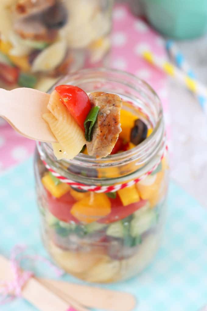 a forkful of the pasta salad being taken out of the mason jar