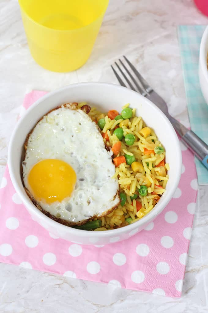 Vegetable Rice & Egg Bowl on a pink polka dot napkin next to a blue fork